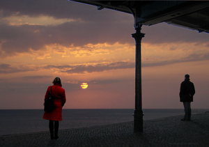 Separated man and woman watching sunset